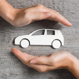 White car on a table, with hands, searching for car insurance no claims discount on a laptop