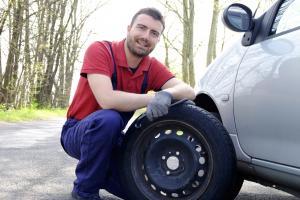 Man in red shirt repairing a car tyre from roadside assistance in Ireland.