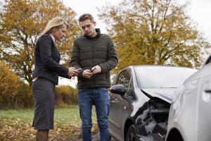 Two drivers exchanging insurance details after a car crash on an Irish road.